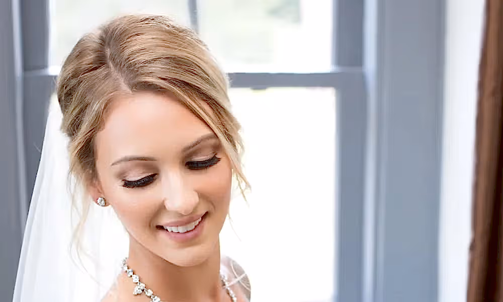 Bride wearing white dress and veil holds bouquet of white flowers. 